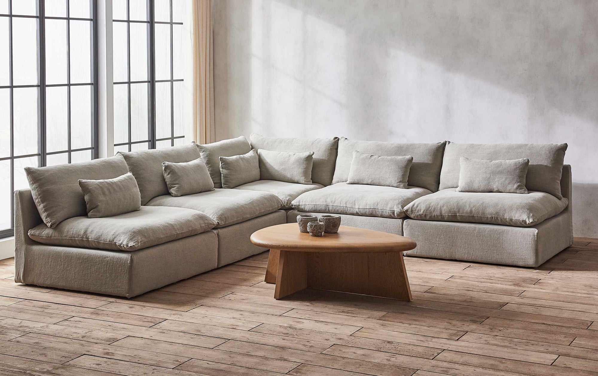An Aria Corner Sectional Sofa placed around the Amina Coffee Table in Tinted Oak.