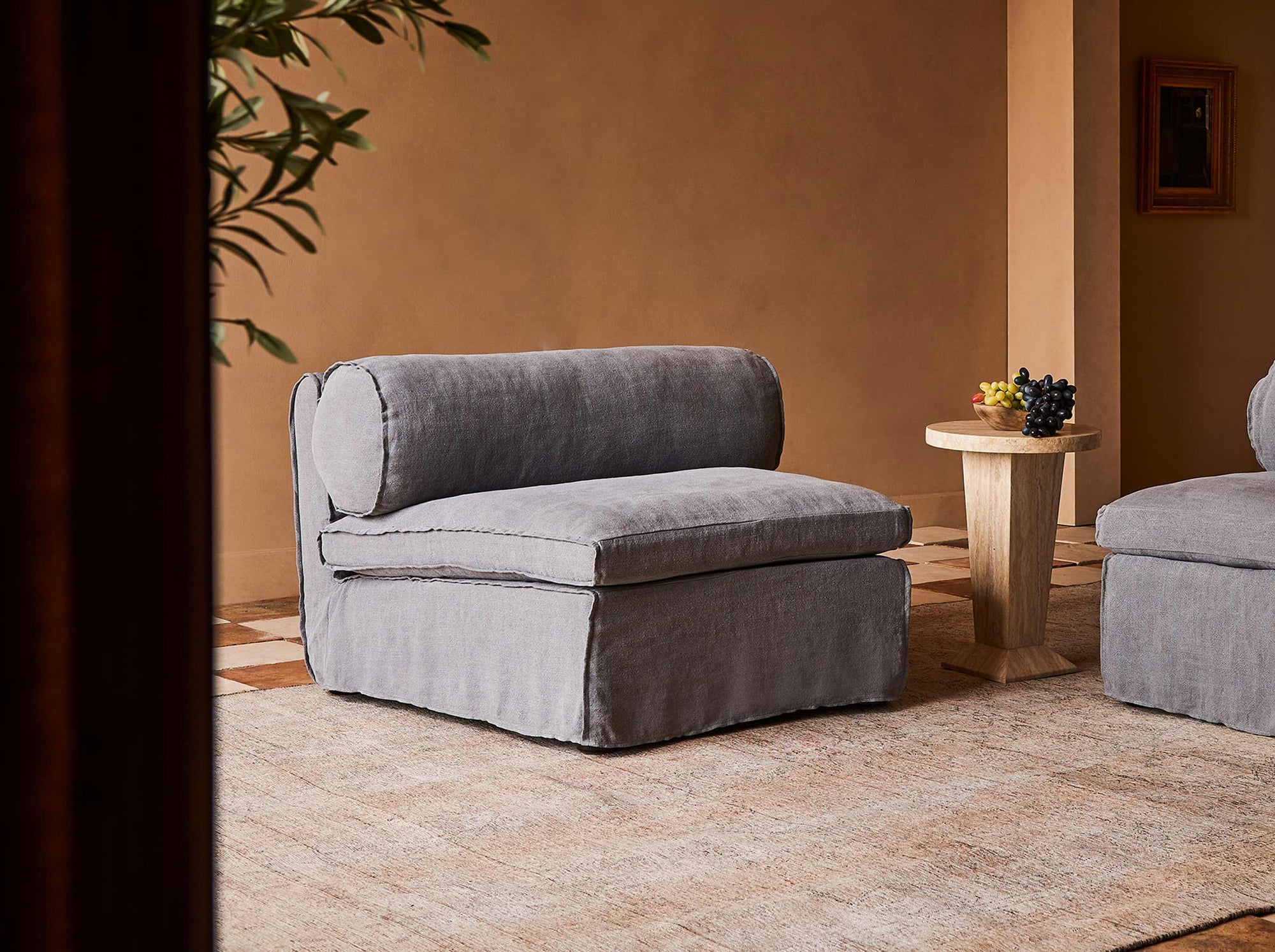 Camino Chair in Ink Cap, a medium cool grey Light Weight Linen, placed in a room next to a side table