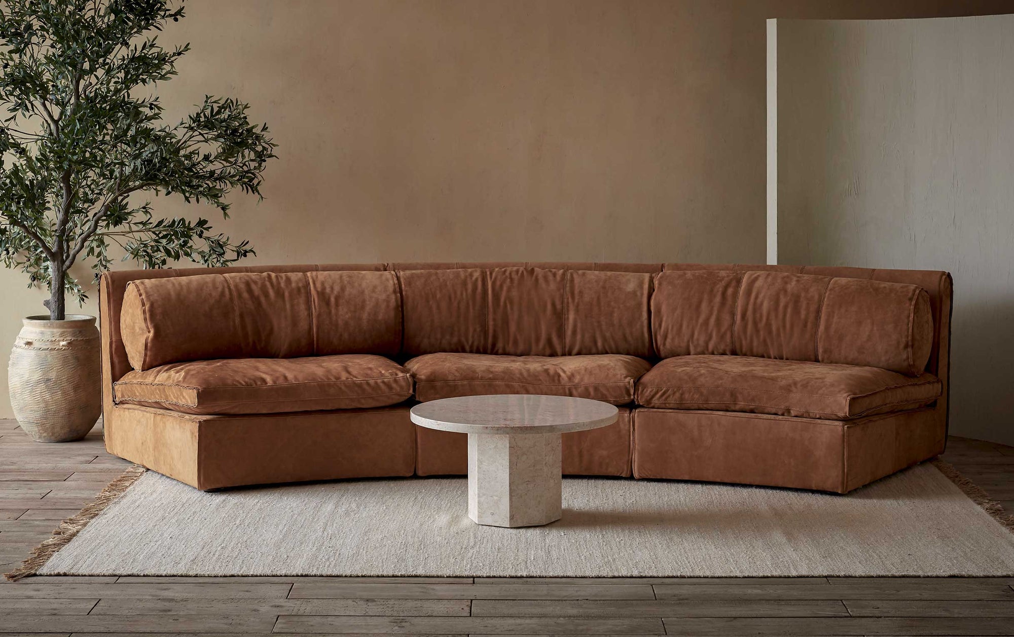 Camino Leather Sectional Sofa in Sunset Canyon, a cognac brown Meridian Leather placed in a room with a coffee table