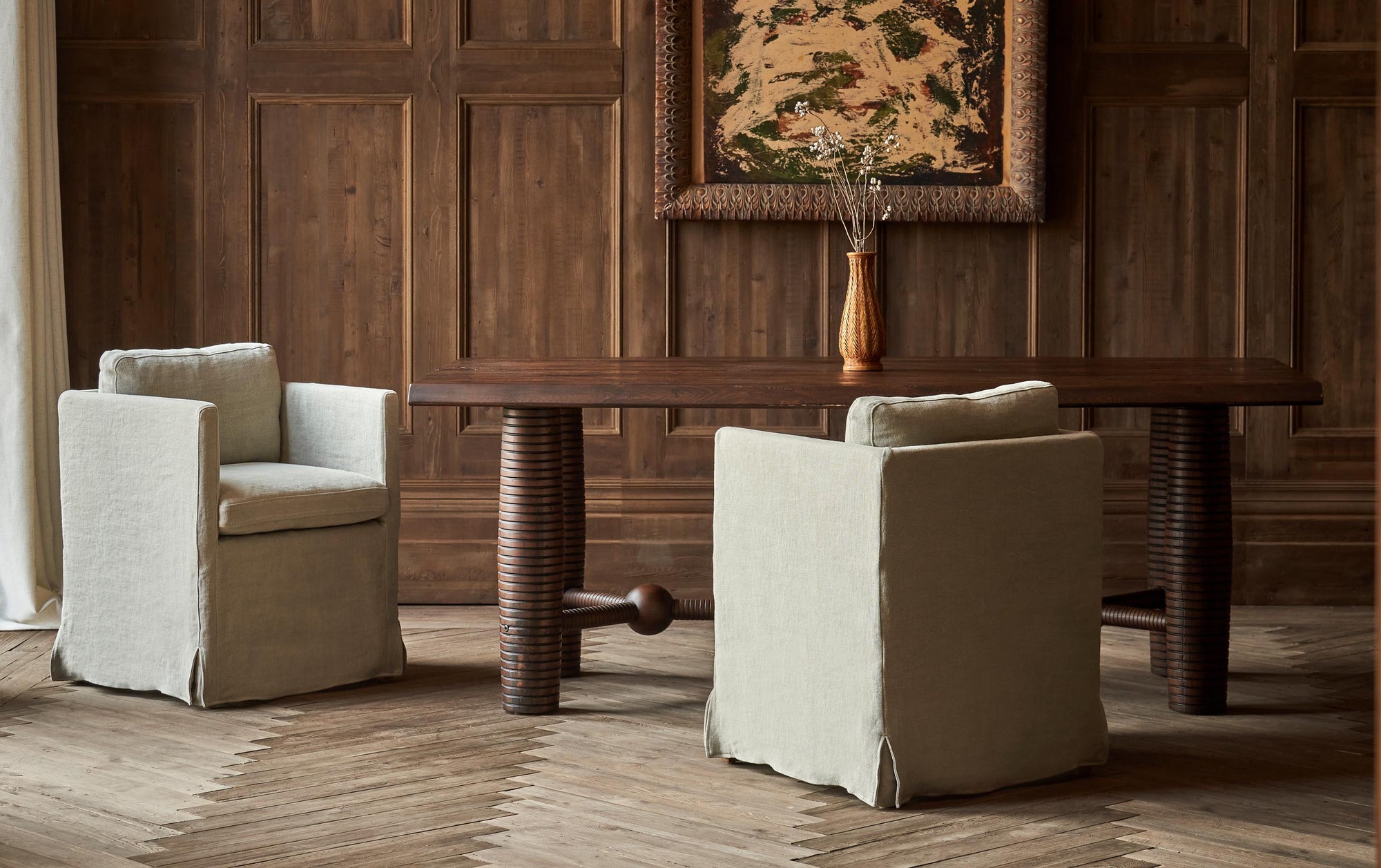 Two Gabriel Dining Chairs in Jasmine Rice, a light warm greige Medium Weight Linen, placed in a decorated room around a Zenia Dining Table