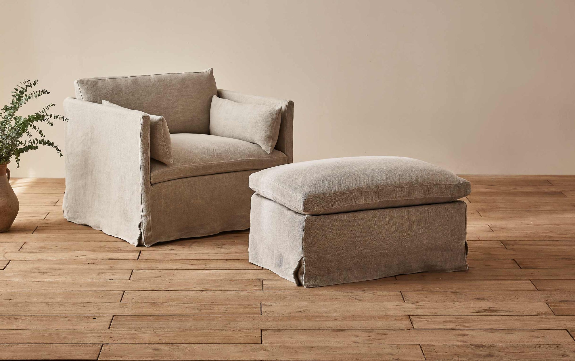 Gabriel Chair Ottoman in Jasmine Rice, a light warm greige Medium Weight Linen, placed in a room in front of the Gabriel Chair