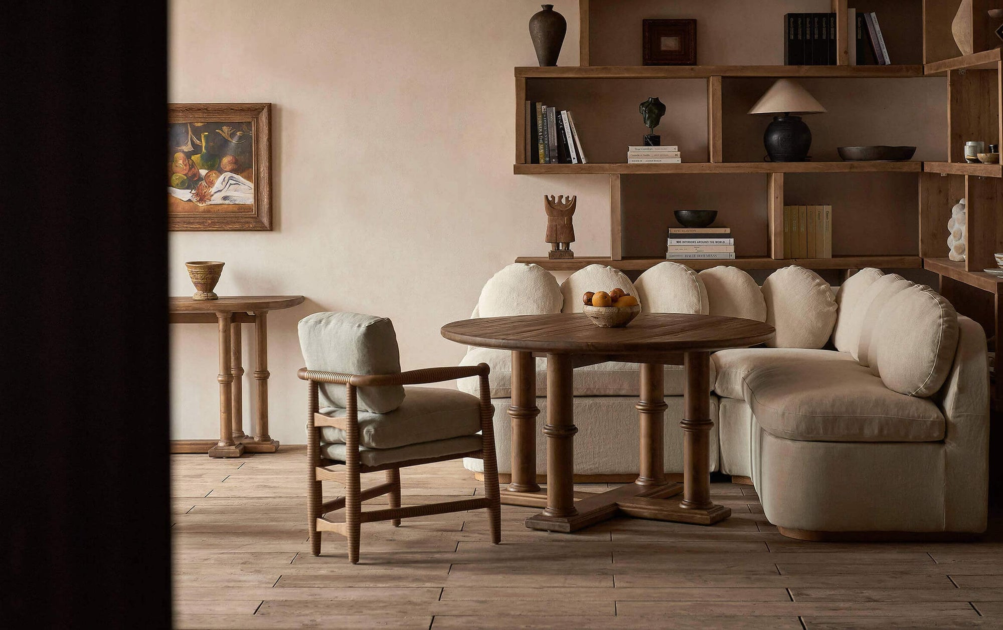 In the center of a dining room is a Pia Dining Table, surrounded by an Olea Banquette and Gio Dining Chair in Heritage Ash, Jasmine Rice.