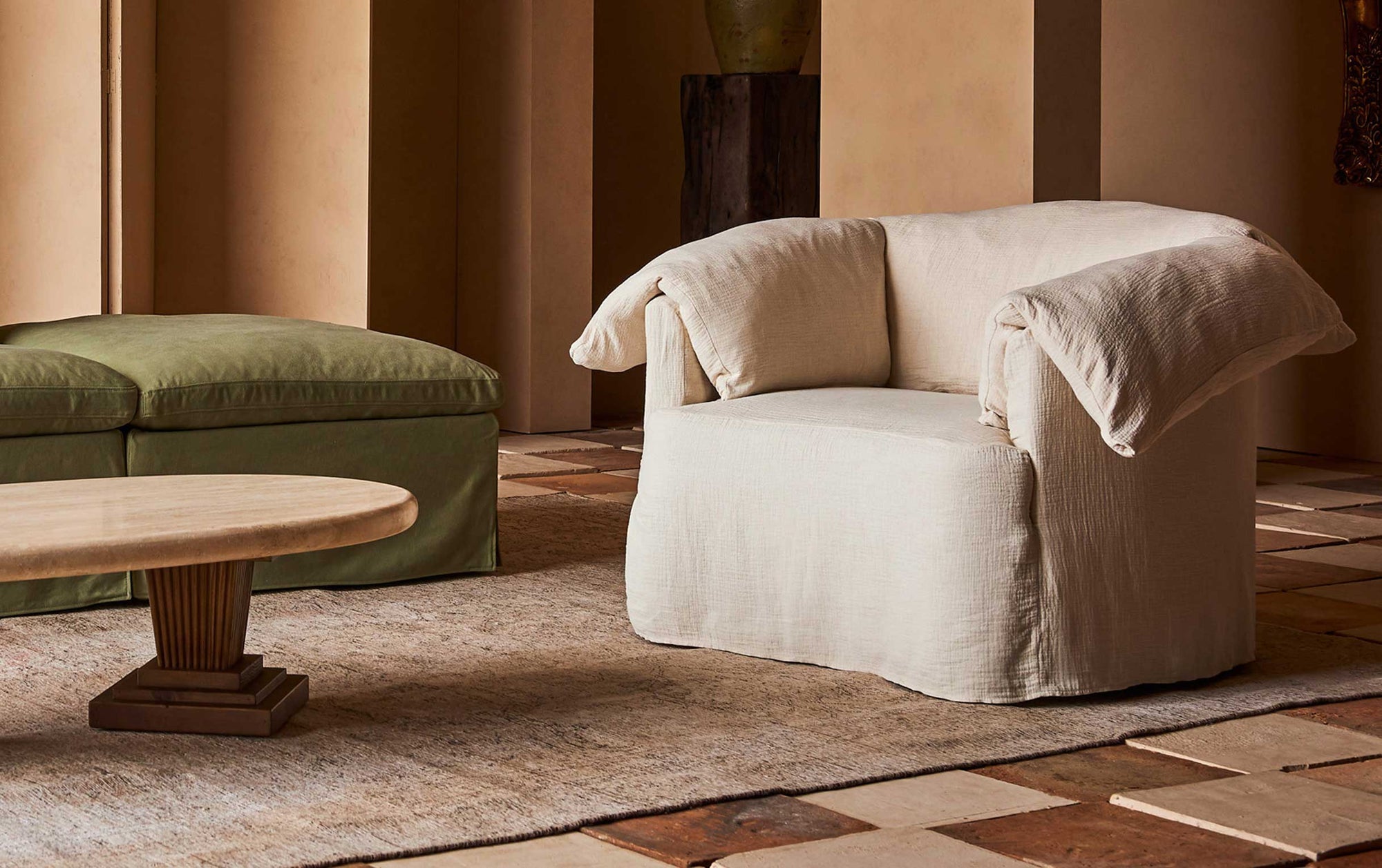 Loula Swivel Chair in Corn Silk Washed Cotton Linen, placed in a room beside the Cordelia Coffee Table and Gabriel Sectional Sofa in Quiet Sage Cotton Canvas