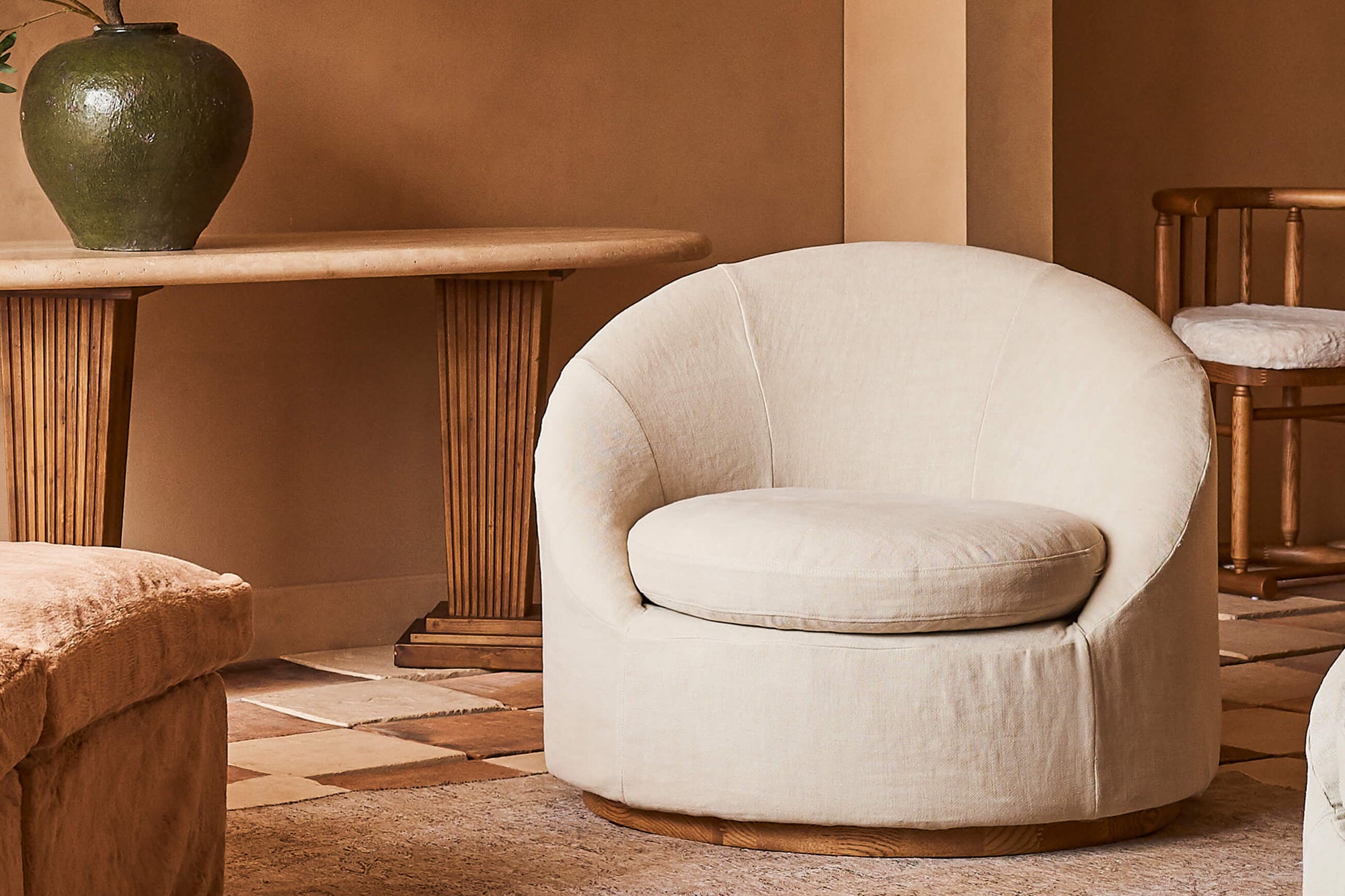 Olea Chair in Warm Oatmeal, a light warm beige Medium Weight Linen, placed in a room with the Cordelia Console Table in the background.