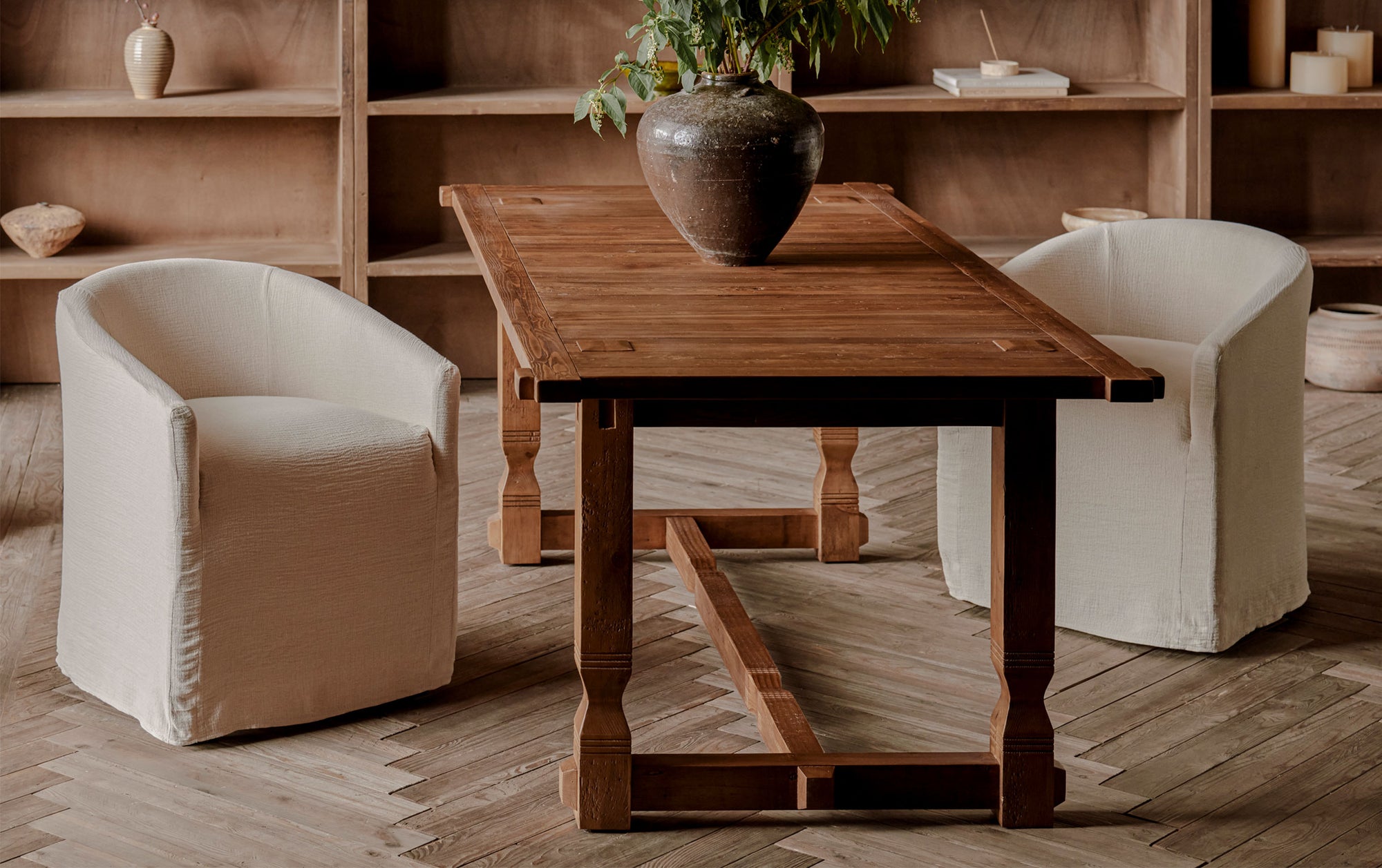 Ora Dining Table in 100% Reclaimed Chinese Heritage Pine, a medium, bosc pear shade with earthy undertones, decorated with a vase of flowers and placed with two Ziki Dining Chairs