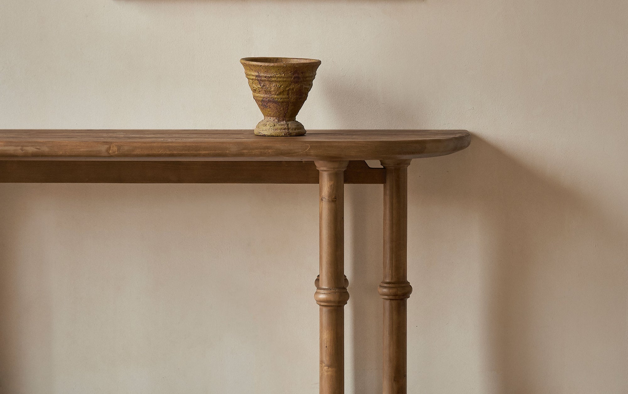 Pia Console Table in 100% Reclaimed Chinese Heritage Pine, a medium, bosc pear shade with earthy undertones, decorated with a vase, placed against a wall