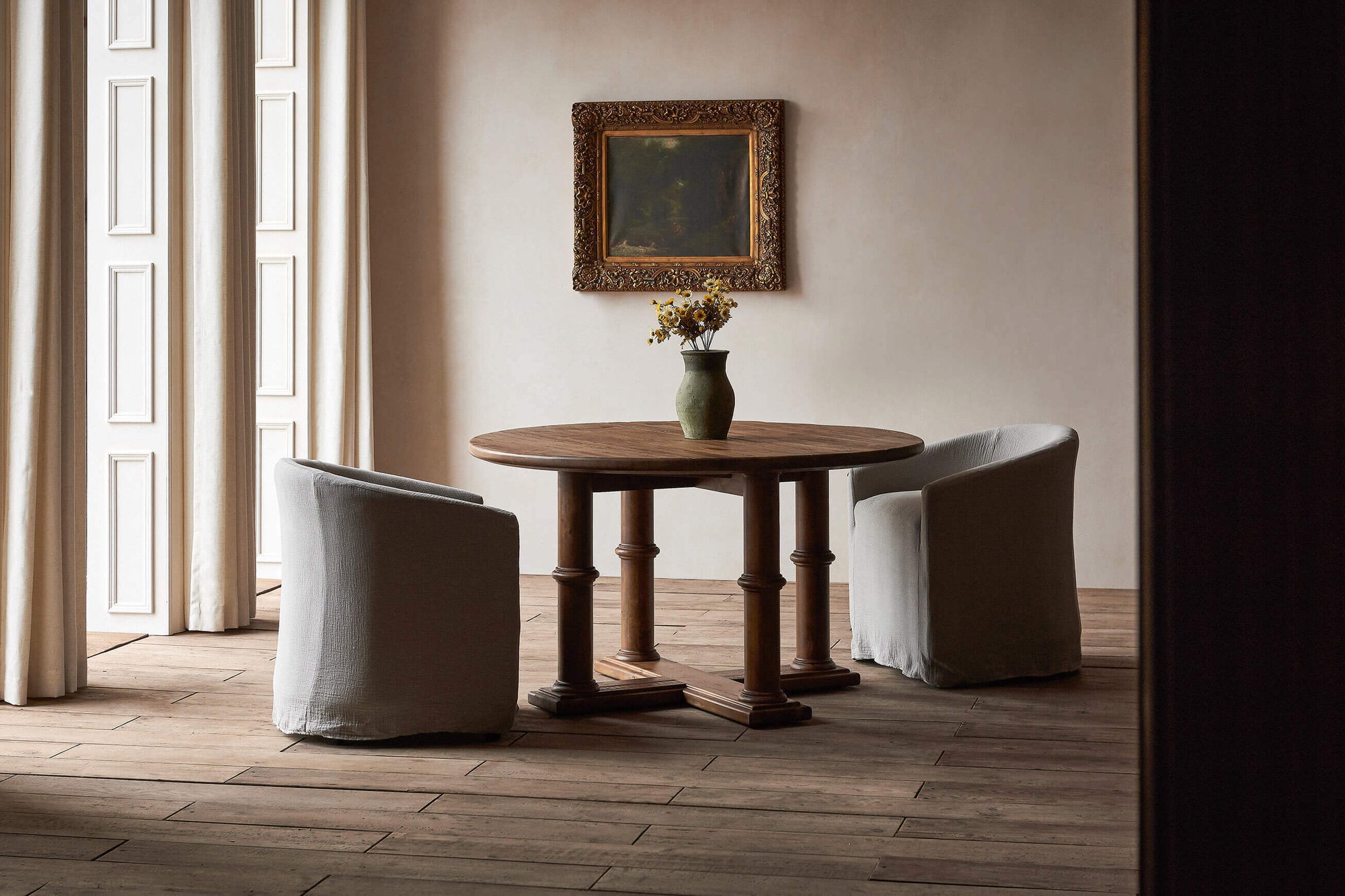 Pia Dining Table in 100% Reclaimed Chinese Heritage Pine, a medium, bosc pear shade with earthy undertones, placed in a room with two Ziki Dining Chairs and a vase of flowers
