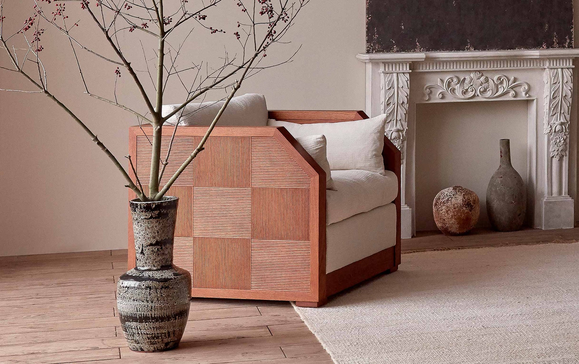 Quincy Chair in Corn Silk, a light beige Washed Cotton Linen, placed in a decorated room on a cream rug next to a potted tree