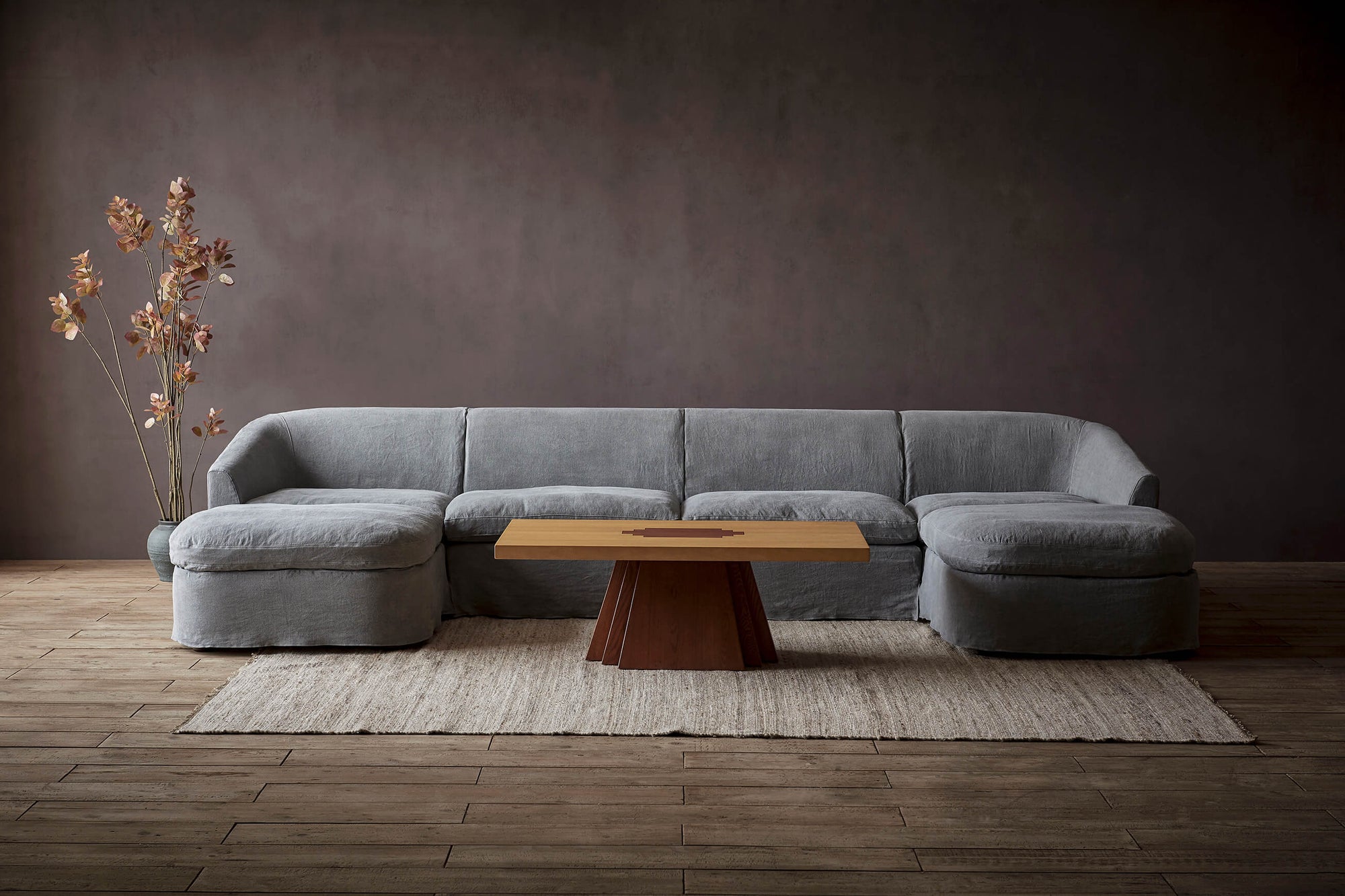 Ziki U-Shape Sectional Sofa in Ink Cap, a medium cool grey Light Weight Linen, placed around a Rigo Coffee Table