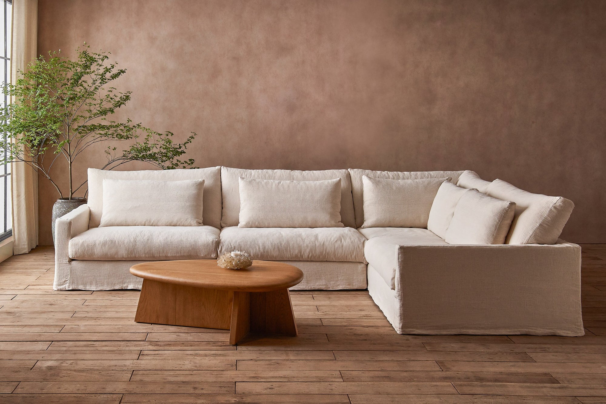 Devyn L-Shape Sectional Sofa in Corn Silk, a light beige Washed Cotton Linen, placed in a sunlit room around the Amina Coffee Table