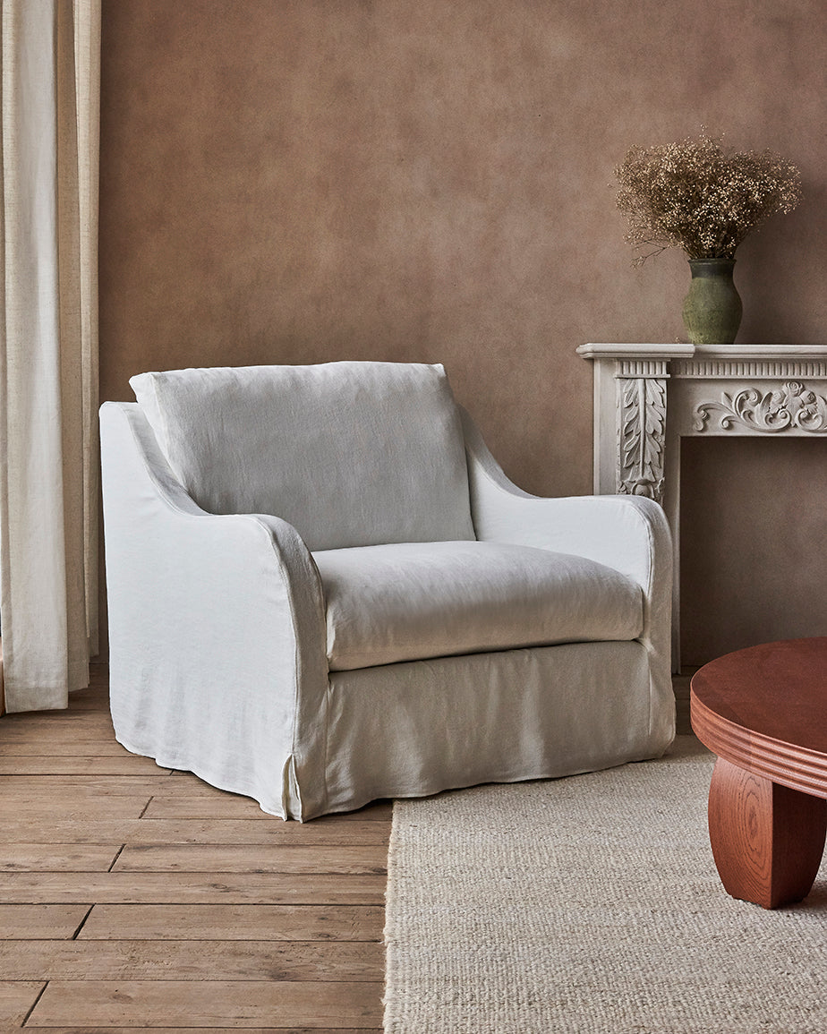 Esmé Chair in Water Lily, a white Light Weight Linen with warm undertones, placed in a sunlit room facing the Pisces Coffee Table
