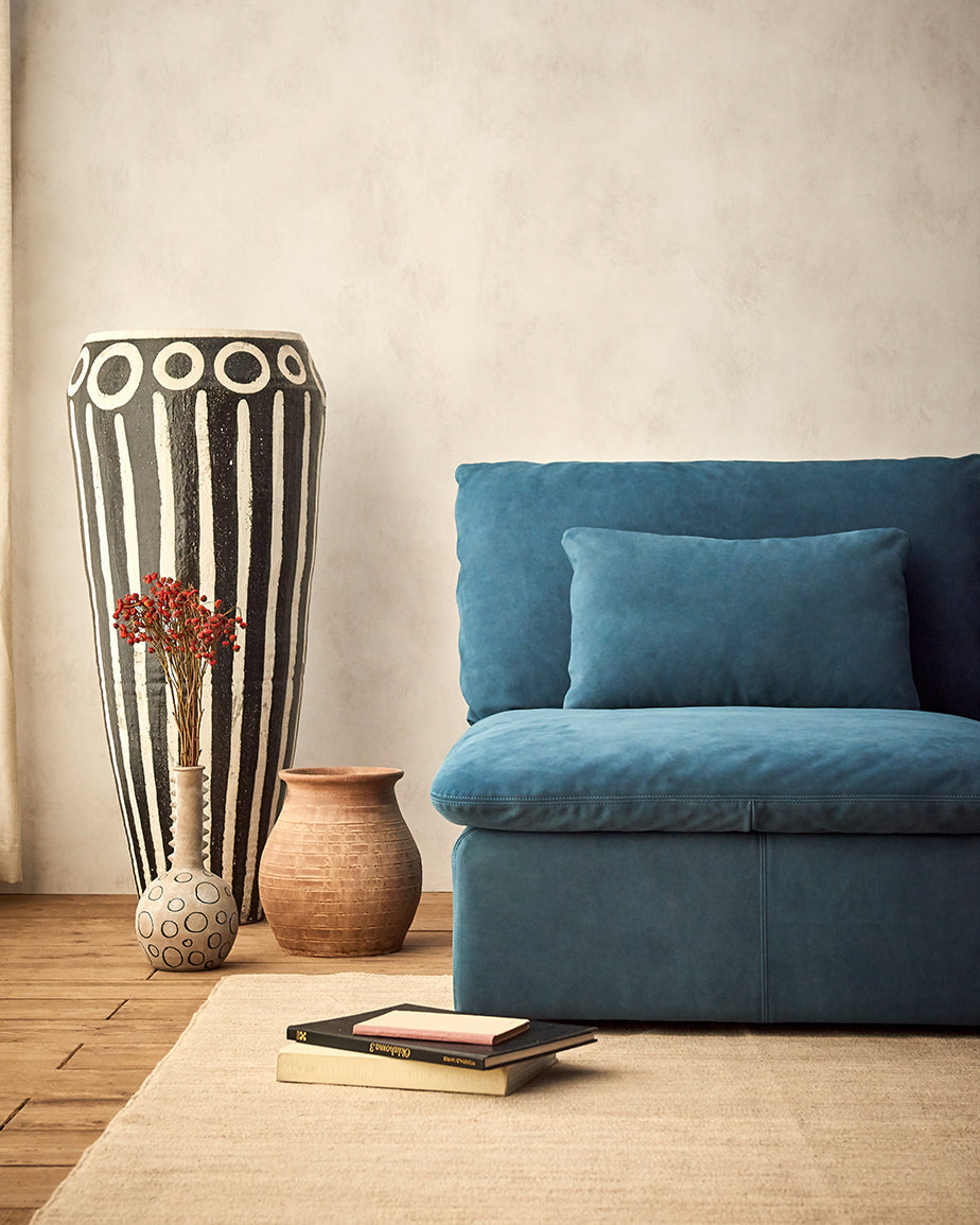 Aria Leather Sofa in North Atlantic, a dark teal blue Meridian Leather, placed in a room next to decorative vases