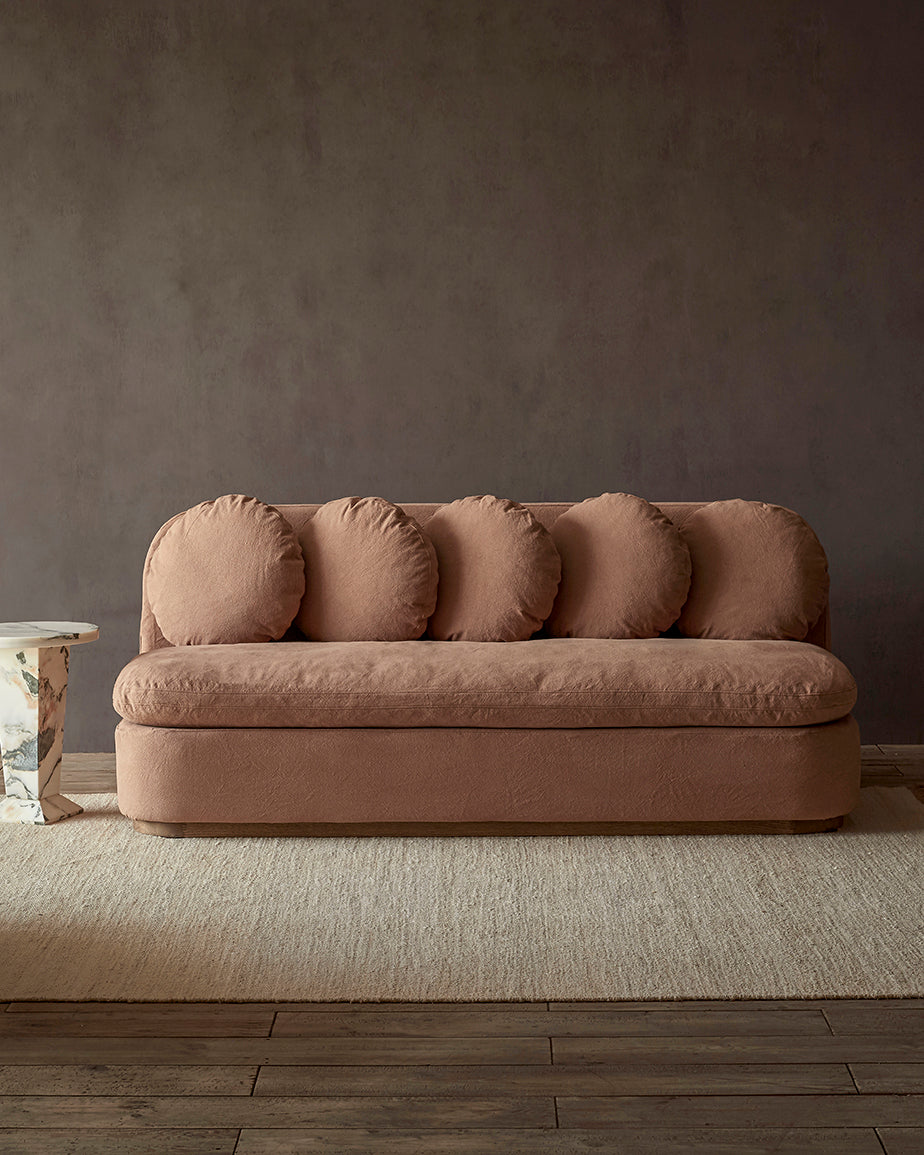 Olea 84" Sofa in Nectarine Dream, a muted terracotta Thread-Dyed Cotton Linen, placed in a room next to a side table
