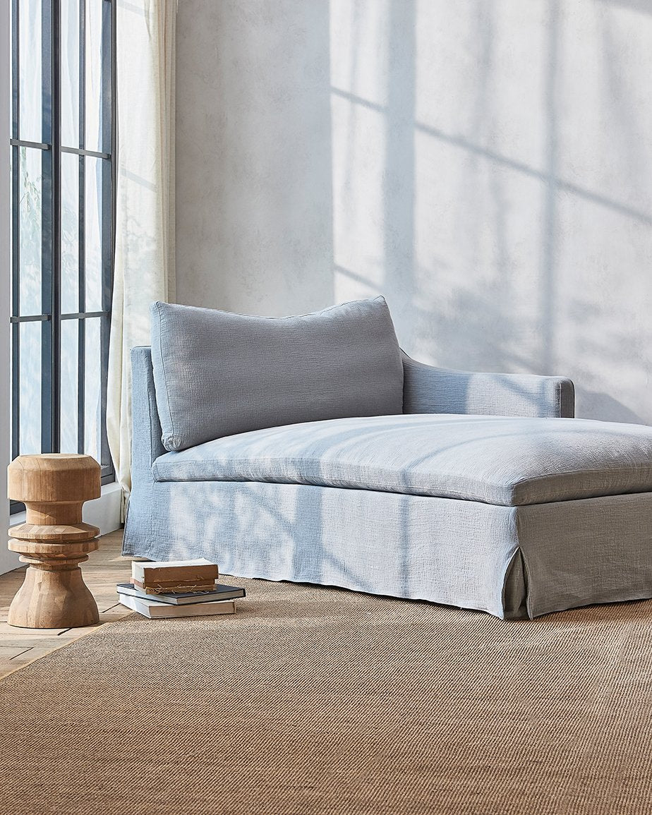 Amelia Daybed in Dried Lavender, a grey-blue Washed Cotton Linen, placed in a sunlit room next to a stack of books