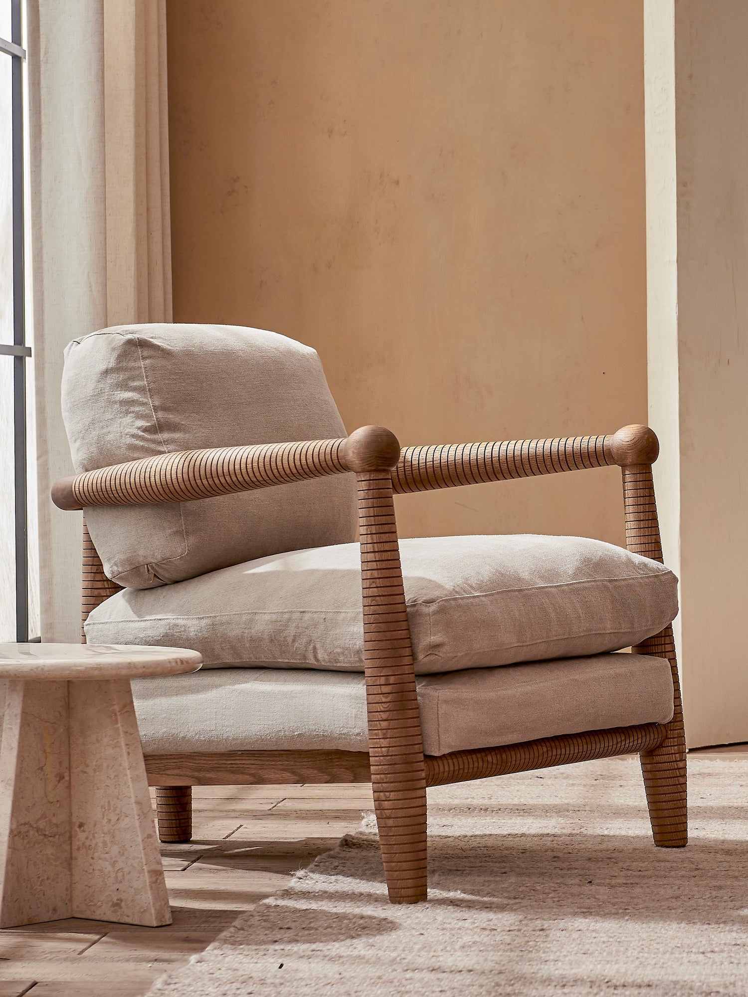Gio Chair in Heritage Ash placed in a sunlit room by the window next to a side table