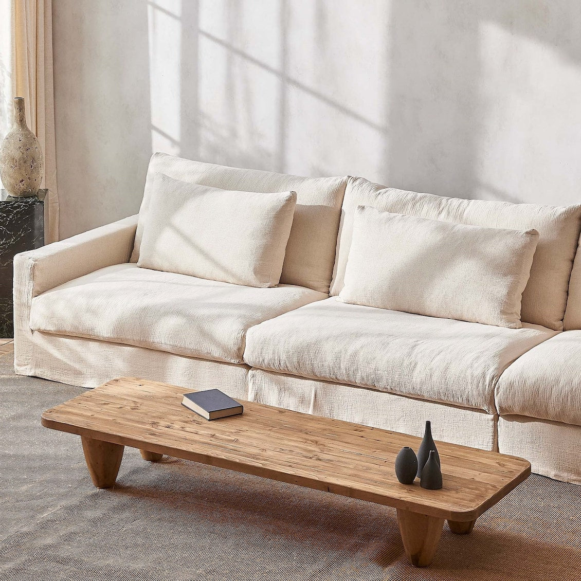 Devyn Sectional Sofa in Corn Silk, a light beige Washed Cotton Linen, placed in a sunlit room with Theo Coffee Table in Heritage Pine