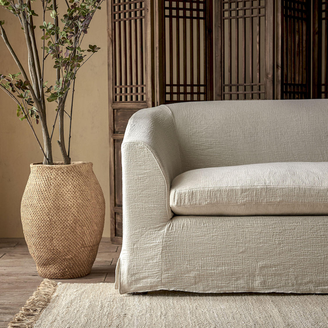 Ziki 96" Sofa in Medium Weight Linen Jasmine Rice placed in a room next to a potted tree