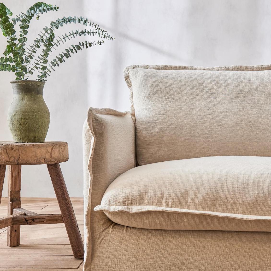 Neva 84" Sofa in Washed Cotton Linen Corn Silk placed in a room next to a stool with a vase