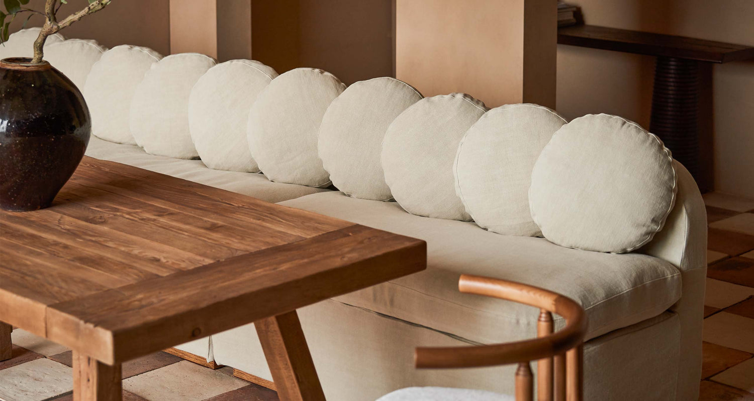 Olea Banquette in Medium Weight Linen Warm Oatmeal placed around the Fasso Dining Table