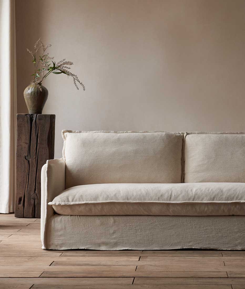 Neva Sofa in Washed Cotton Linen Corn Silk with a pillar and potted plant in the background