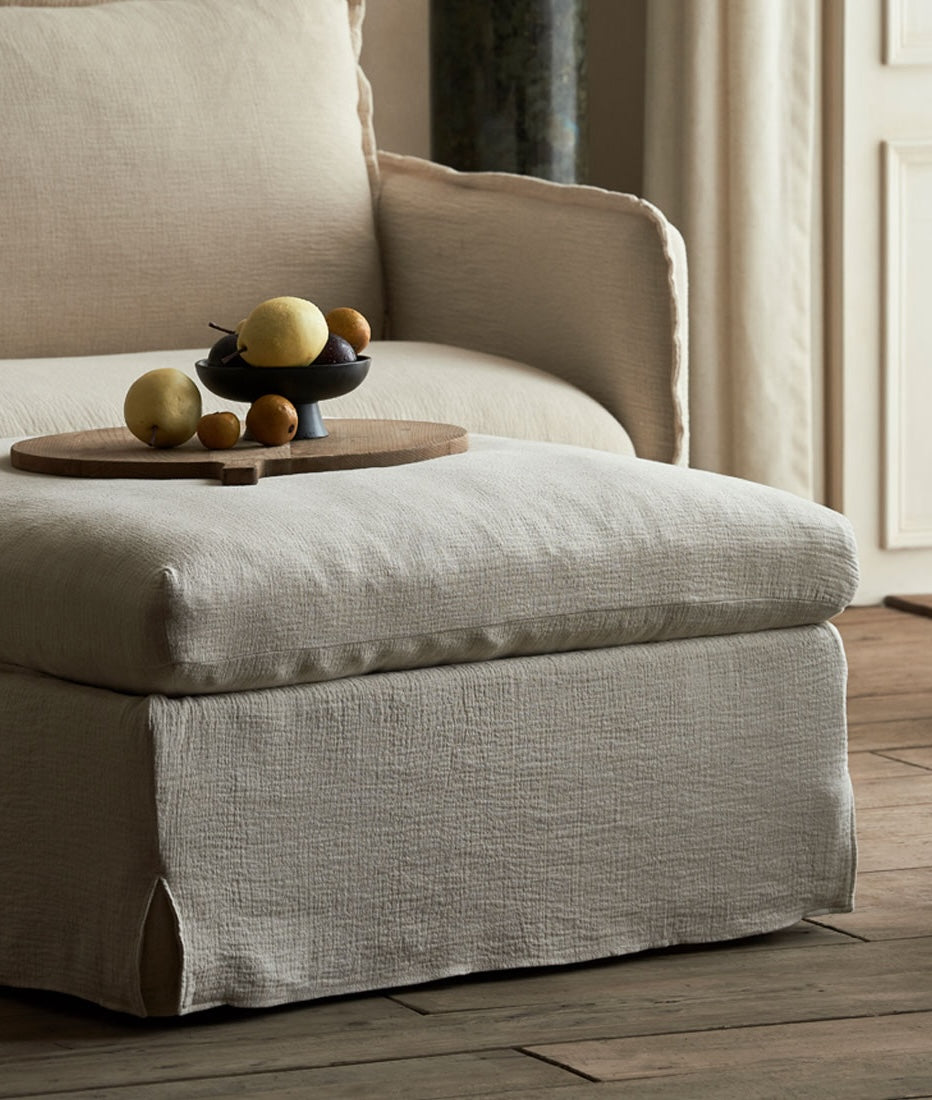 Esme Storage Ottoman in Washed Cotton Linen Corn Silk with a tray of fruit placed on the surface