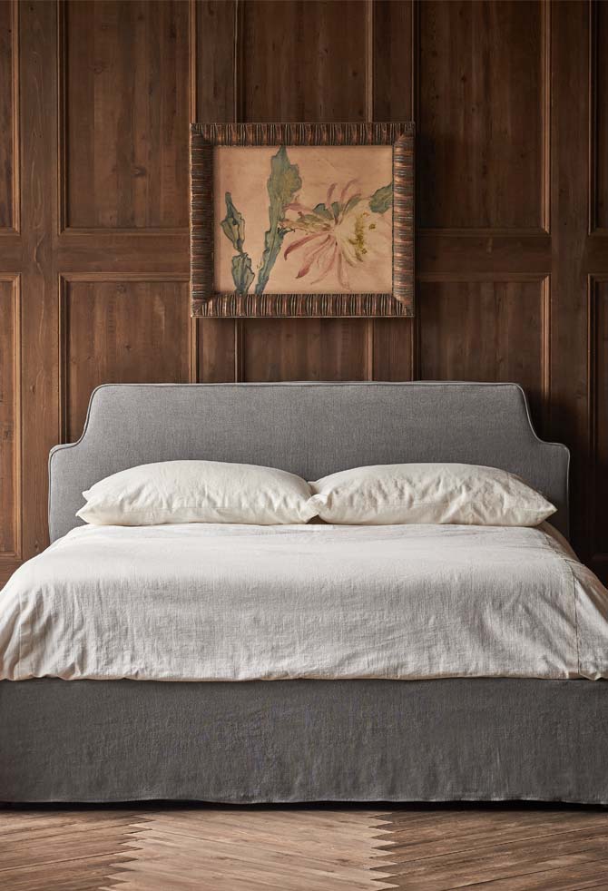 An Amelia Bed in Light Weight Linen Ink Cap is placed in the center of a room.