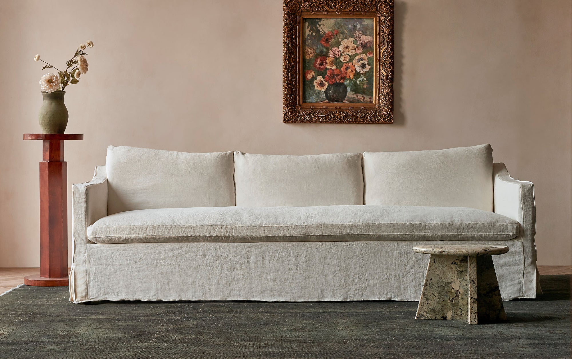 Amelia 96" Sofa in Water Lily, a white Light Weight Linen with warm undertones, placed in a room beside a marble side table and vase.