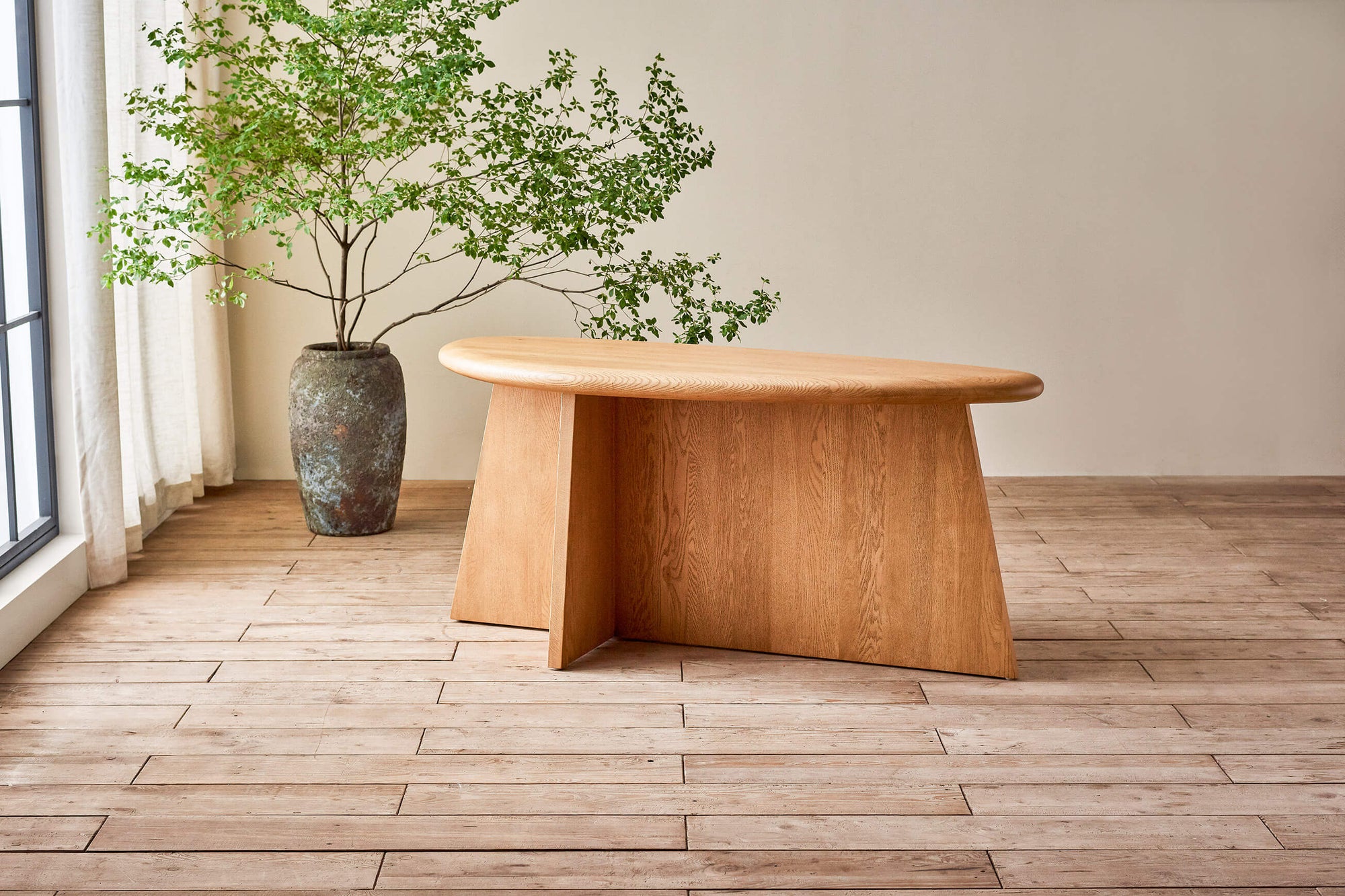 Amina Console Table in Tinted Oak placed next to a potted tree