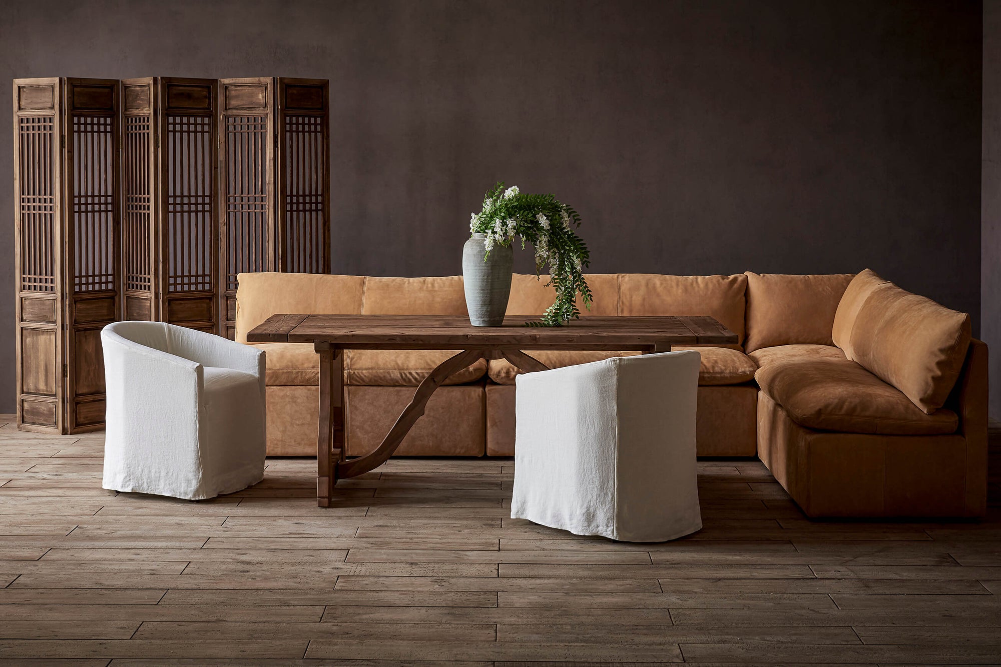 Aria Leather Banquette in Mojave Glow, a tan Meridian Leather, placed with two Ziki Dining Chairs around a Leona Dining Table with a vase of flowers