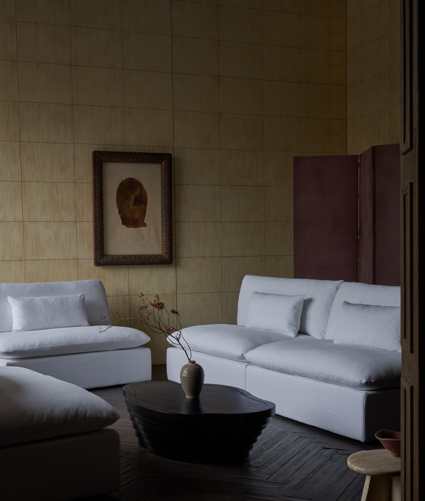 A modern living room interior featuring a Sixpenny Aria sectional in water lily,
a Sixpenny Terra coffee table in inky oak, a beige tiled wall, and framed wall art.