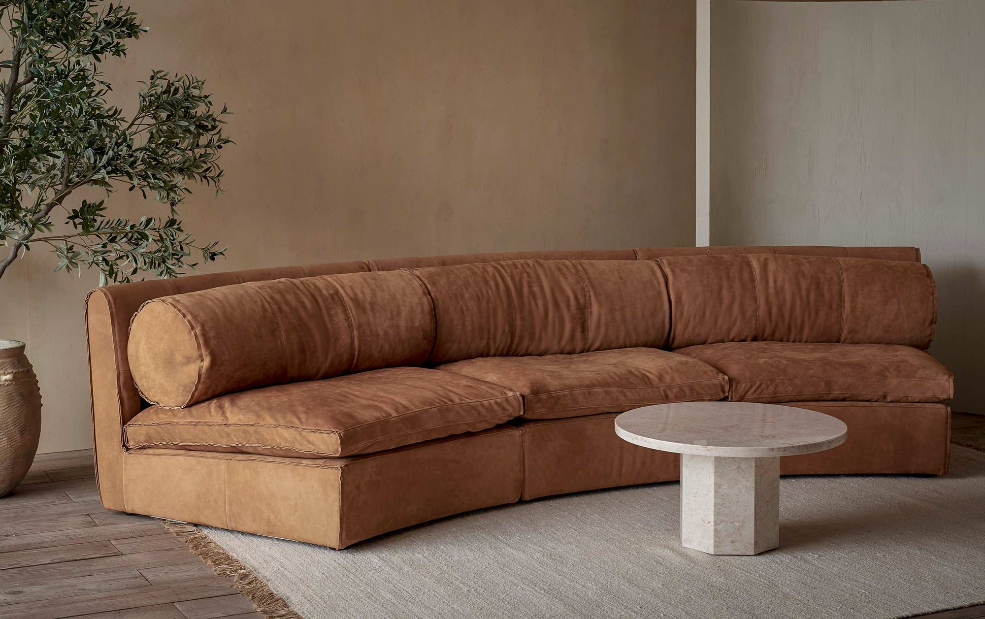 Camino Leather Sectional Sofa in Sunset Canyon, a cognac brown Meridian Leather placed in a room with a coffee table