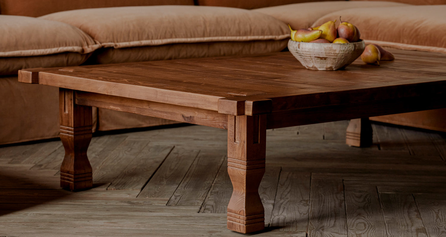 A bowl of fruit is placed on top of the Ora Coffee Table in Heritage Pine