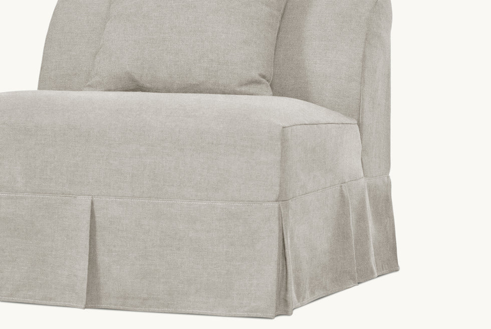 Detail view of the pleated skirt on the Dalia Armless Chair in Jasmine Rice, a light warm greige Medium Weight Linen