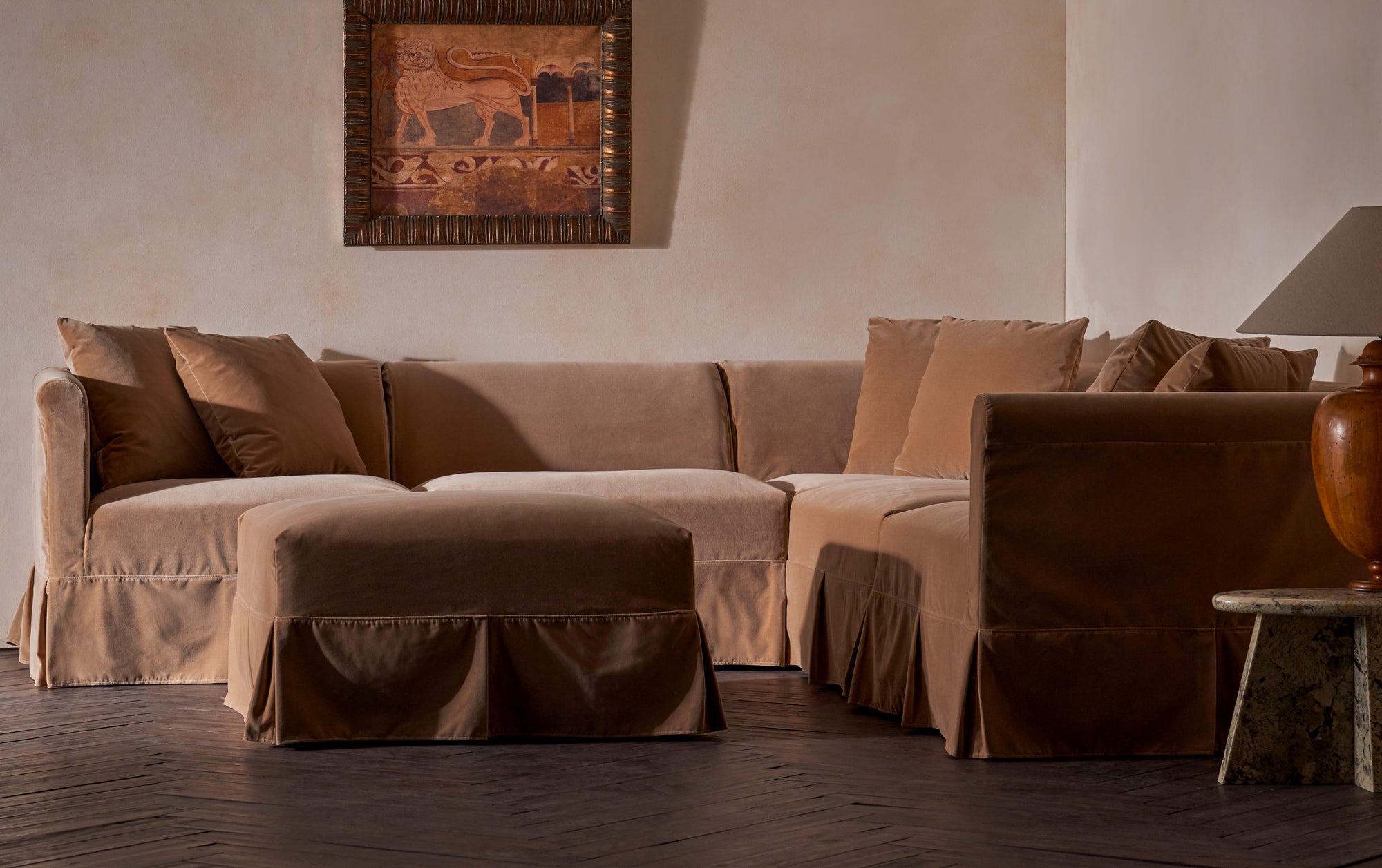 Dalia Corner Sectional in Daily Bread, a warm, golden brown Washed Cotton Velvet, placed in a decorated room with matching Dalia Sectional Ottoman.