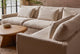 Slide #6 Close up of Devyn L-Shape Sectional Sofa in Corn Silk, a light beige Washed Cotton Linen, placed in a sunlit room around the Amina Coffee Table
