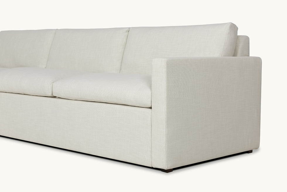 Close up view of Devyn Sleeper Chaise Sectional in Young Coconut, a powdery white Recycled Poly Linen