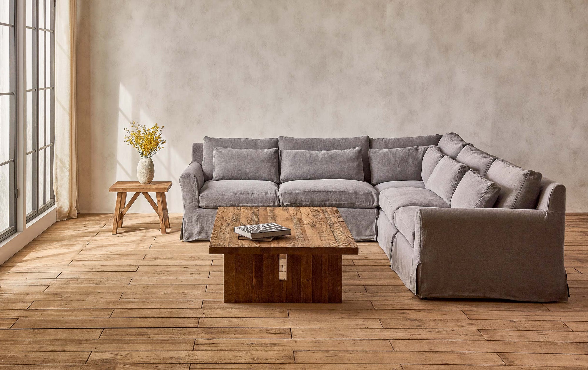Elias Corner Sectional Sofa in Ink Cap, a medium cool grey Light Weight Linen, placed in a sunlit room with the Kai Coffee Table