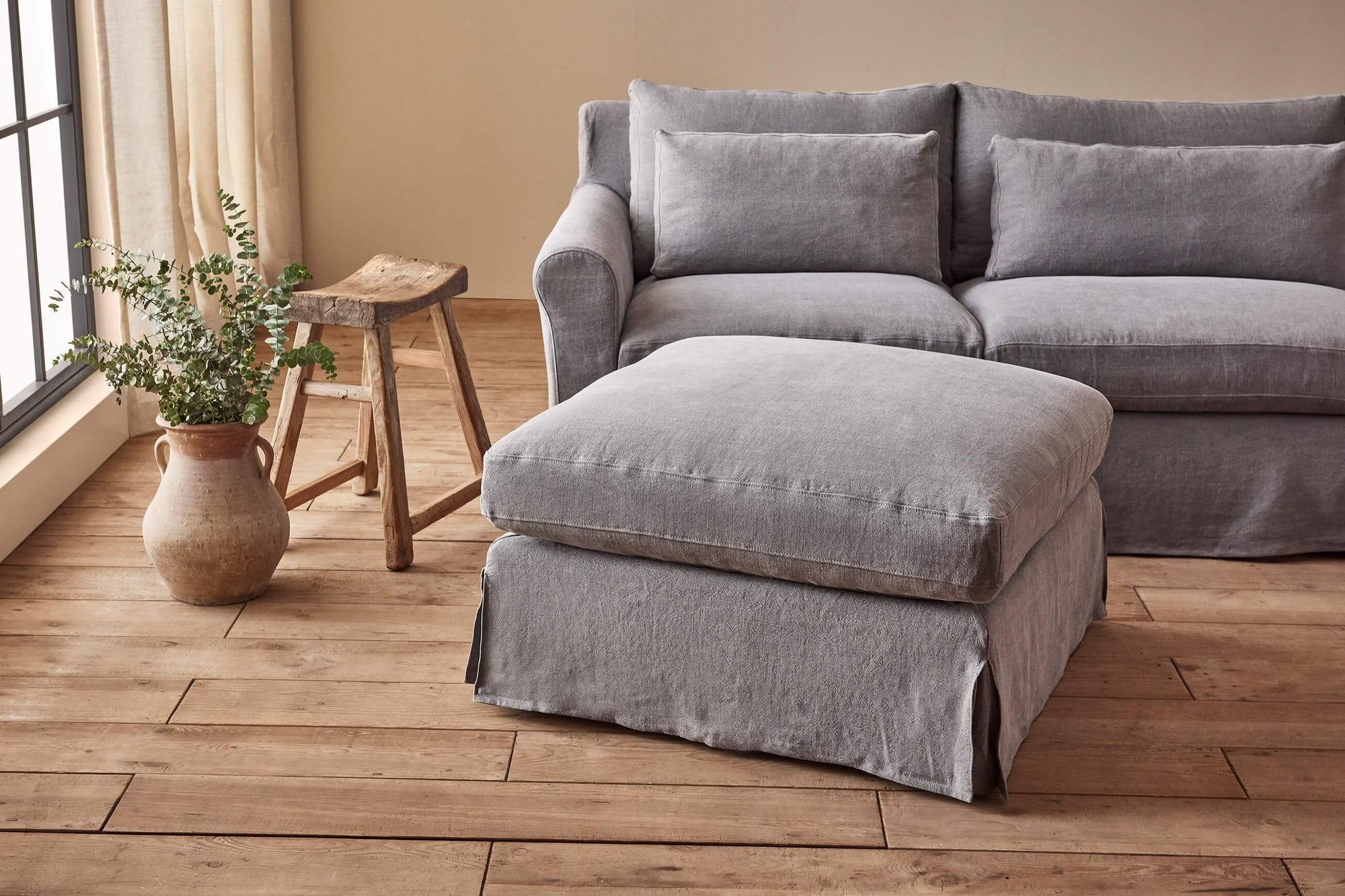 Elias Sectional Ottoman in Ink Cap, a medium cool grey Light Weight Linen, placed in a room with the Elias Sectional Sofa
