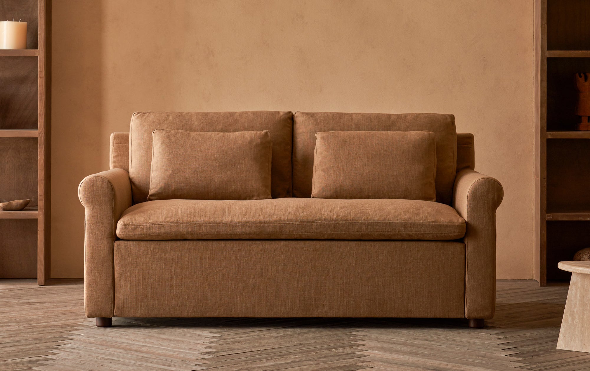 Elias Sleeper Sofa in Branch Out, a golden brown linen-like recycled polyester, placed in a room in between two bookcases