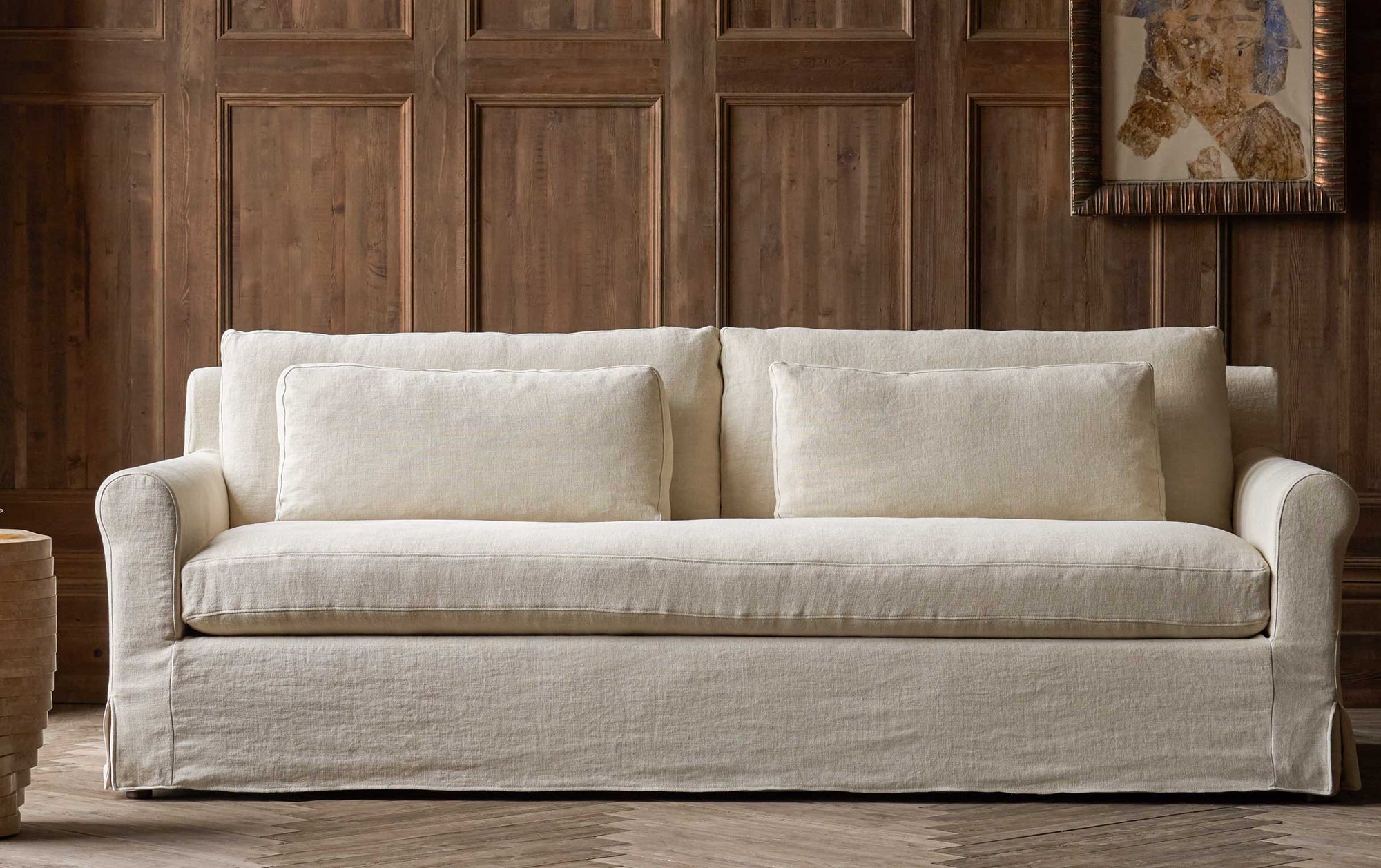 Elias 96" Sofa in Warm Oatmeal, a light warm beige Medium Weight Linen, placed in front of a wood paneled wall 