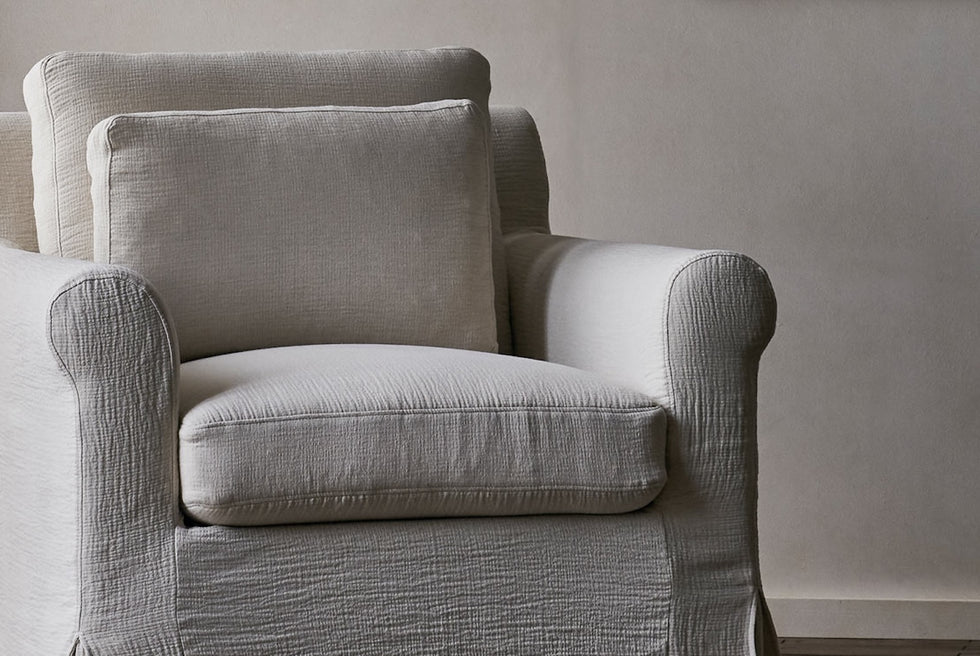 Close up of Elias Swivel Chair in Corn Silk, a light beige Washed Cotton Linen, in front of a greige wall 