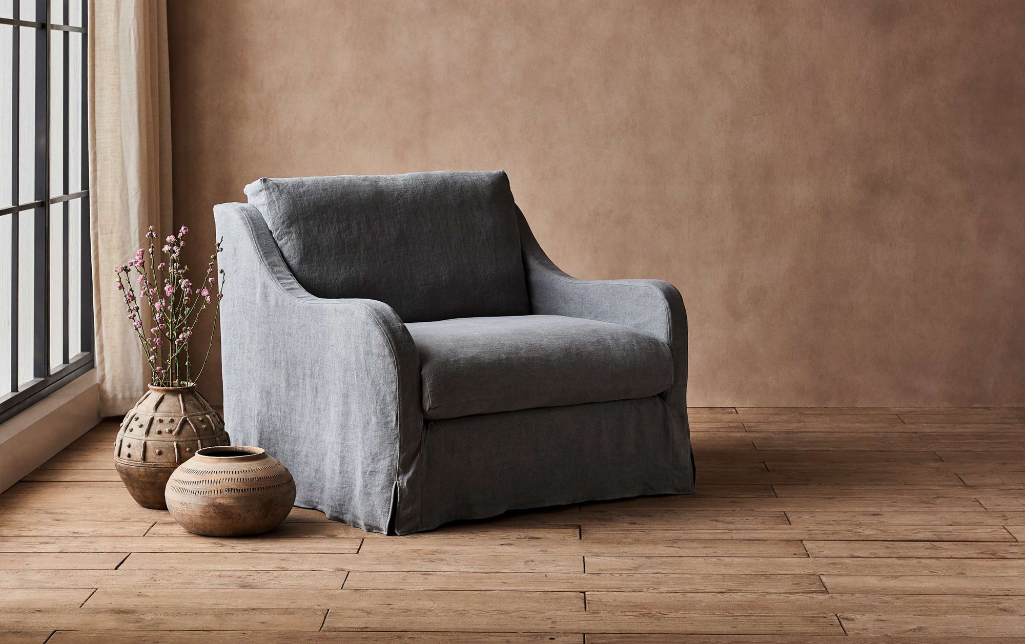 Esmé Chair in Ink Cap, a medium cool grey Light Weight Linen, placed in a room