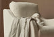 Slide #6 Close up of Esme Glider Chair in Corn Silk, a light beige Washed Cotton Linen, in a sunlit room by a window with a blanket and stuffed toy placed on the seat