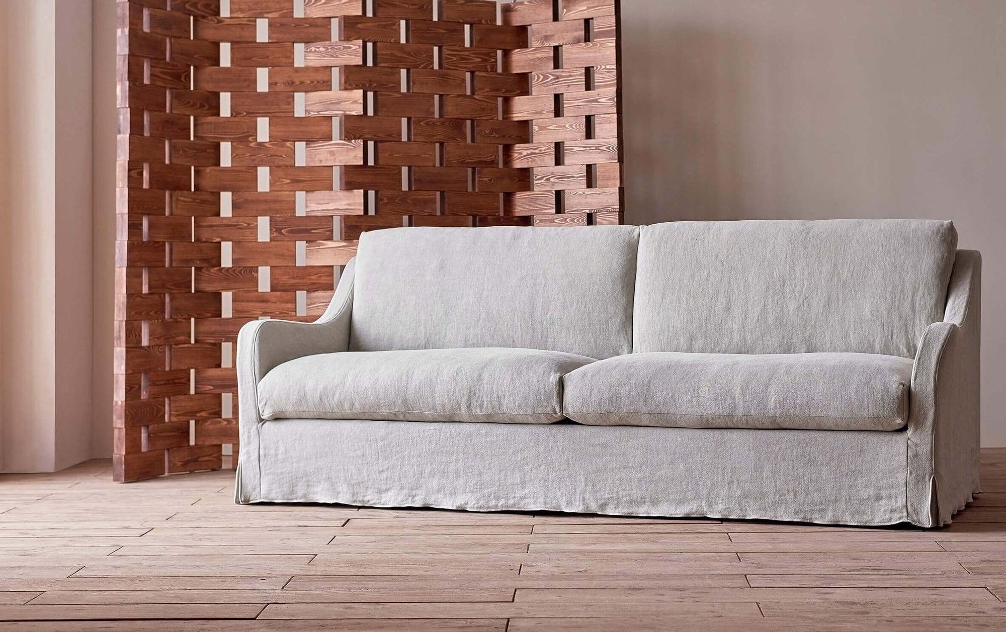 Esmé 96" Sofa in Jasmine Rice, a light warm greige Medium Weight Linen, in front of a wooden folding screen