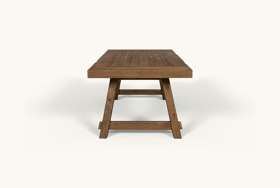 Side view of Fasso Dining Table in 100% Reclaimed Chinese Heritage Pine, a medium, bosc pear shade with earthy undertones