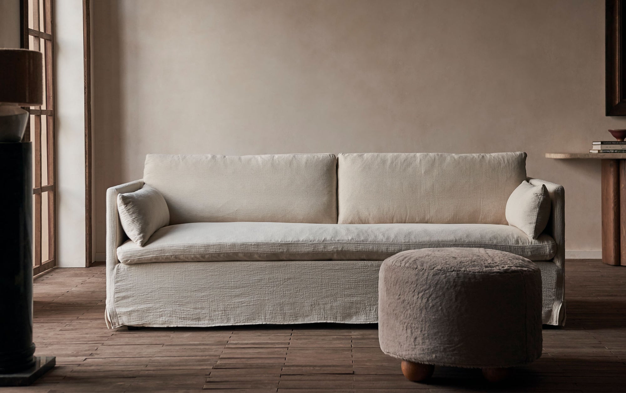 Gabriel 84" Sofa in Corn Silk, a light beige Washed Cotton Linen, placed behind an ottoman in the foreground.