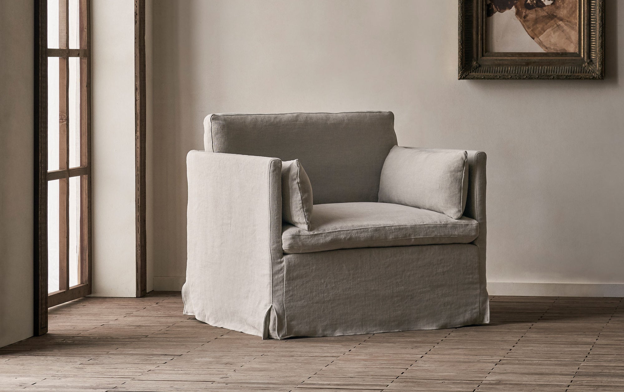 Gabriel Swivel Chair in Jasmine Rice, a light warm greige Medium Weight Linen, in front of a greige wall with a hanging framed painting