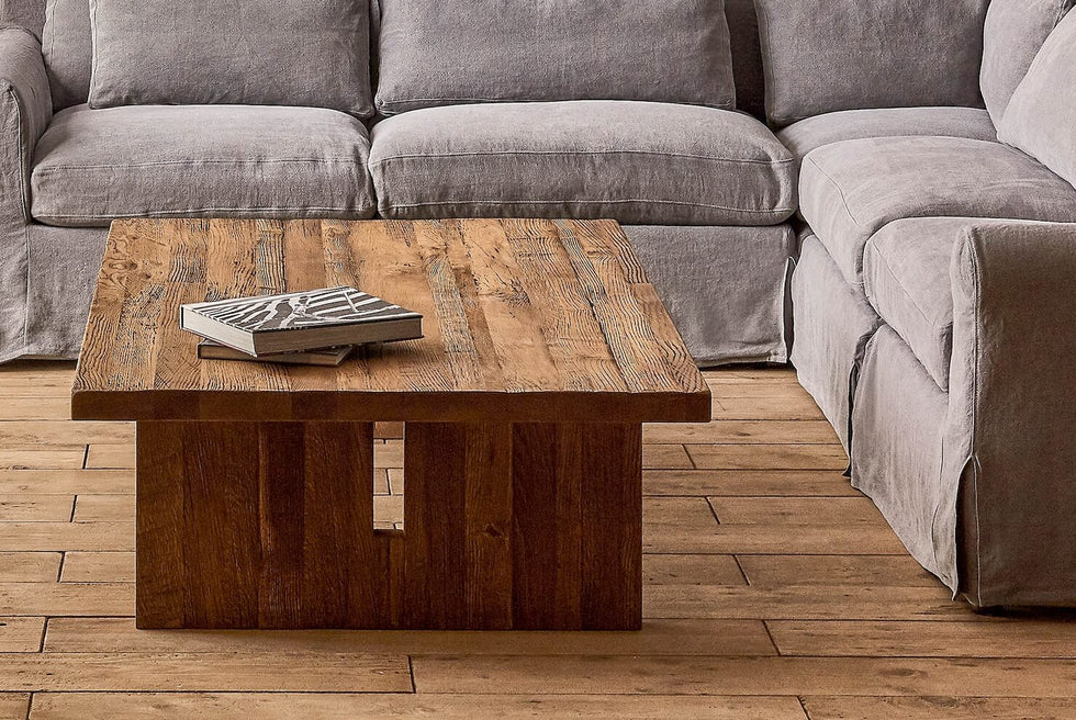 Kai Coffee Table in 100% Reclaimed Austrian Heritage Oak, topped with two coffee table books and placed in front of an Elias Corner Sectional in Ink Cap.