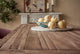 Slide #7 Close up of Leona Dining Table in 100% Reclaimed Chinese Heritage Pine, a medium, bosc pear shade with earthy undertones, placed in a decorated room with a bowl of pears on it.