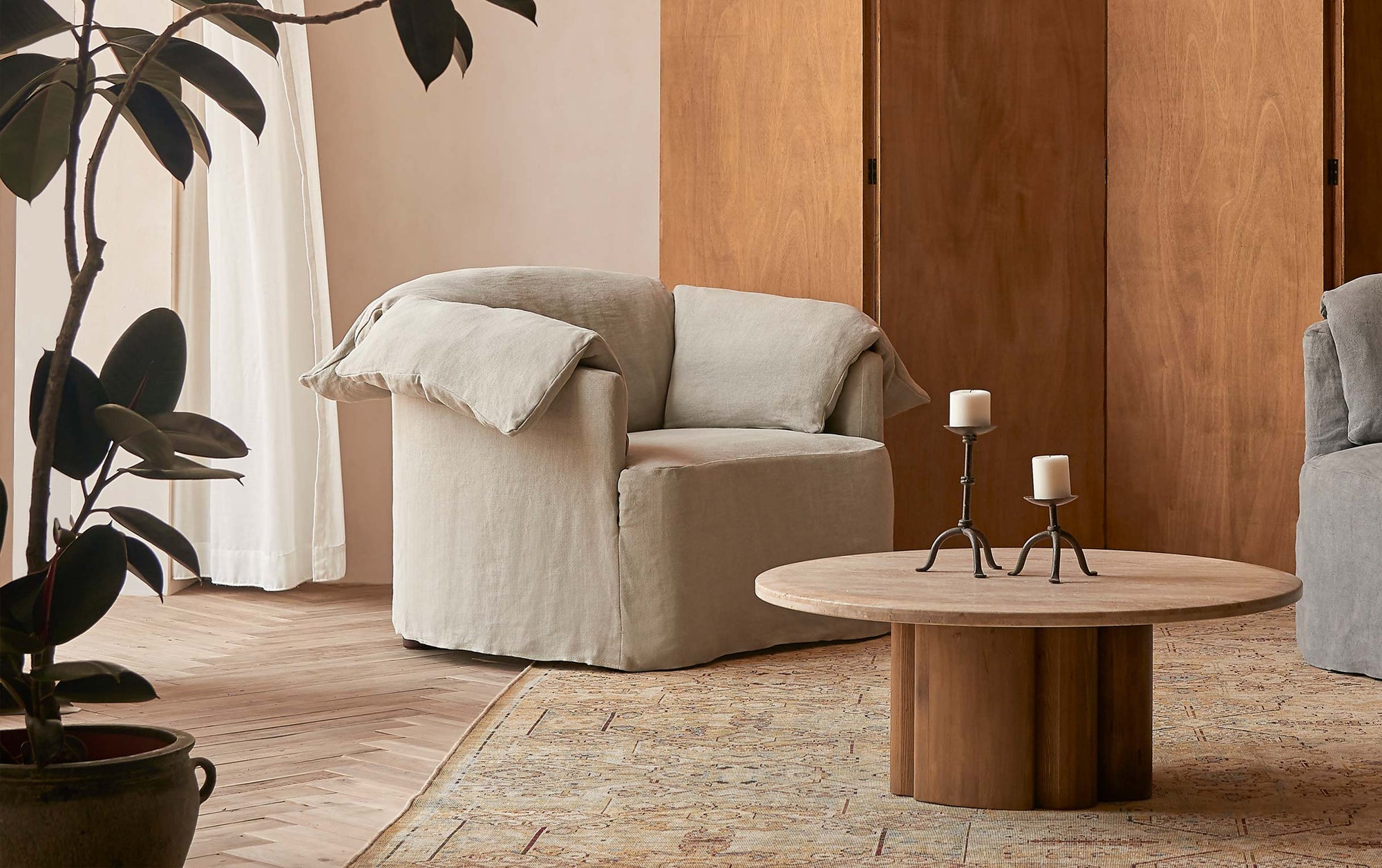 Loula chair in Jasmine Rice, a light warm greige Medium Weight Linen, placed in a room facing a coffee table